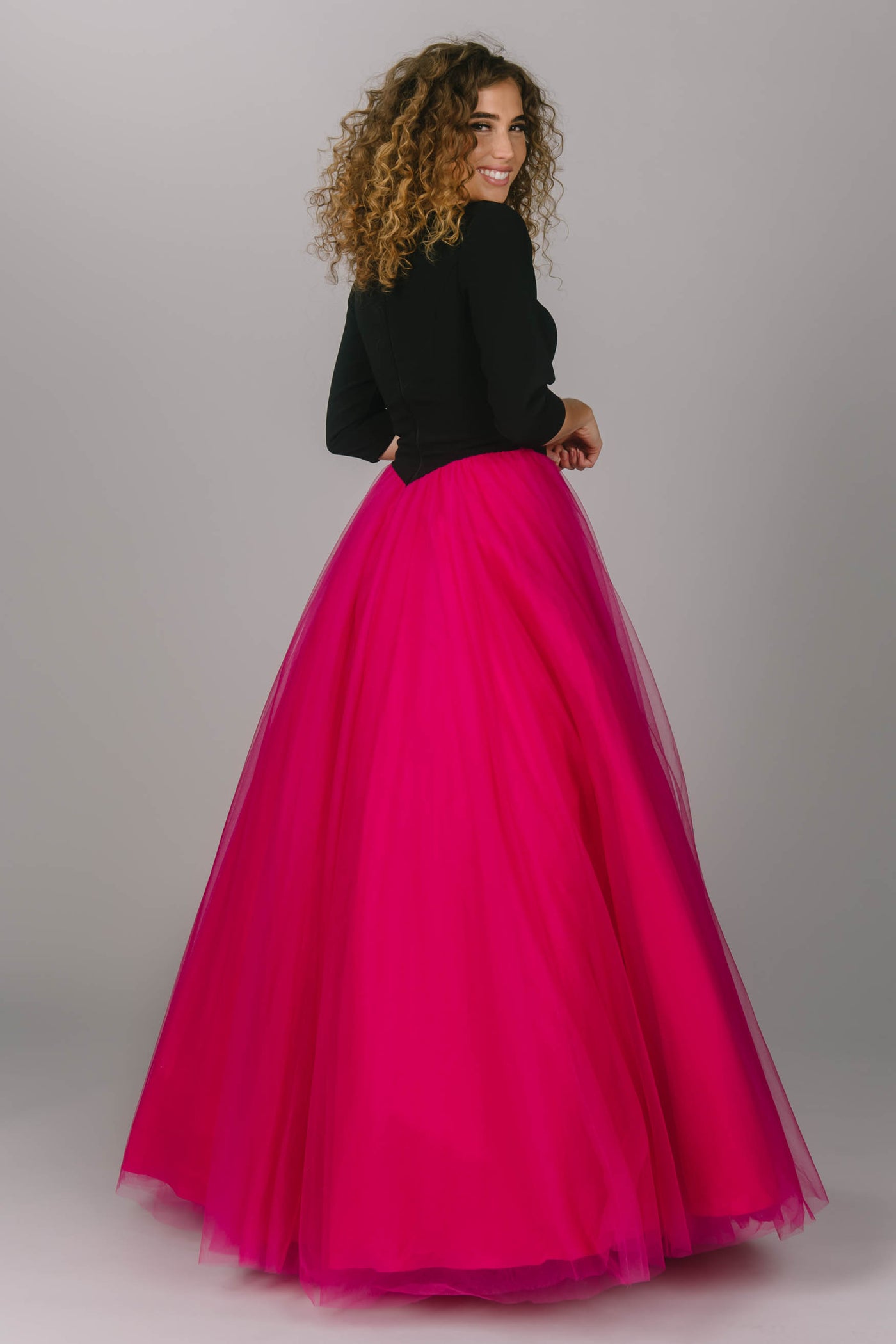 Modest prom ballgown with pink tulle skirt and black top. Sleeves are quarter length and it has a high scoop neckline. This is the perfect modest prom ballgown.