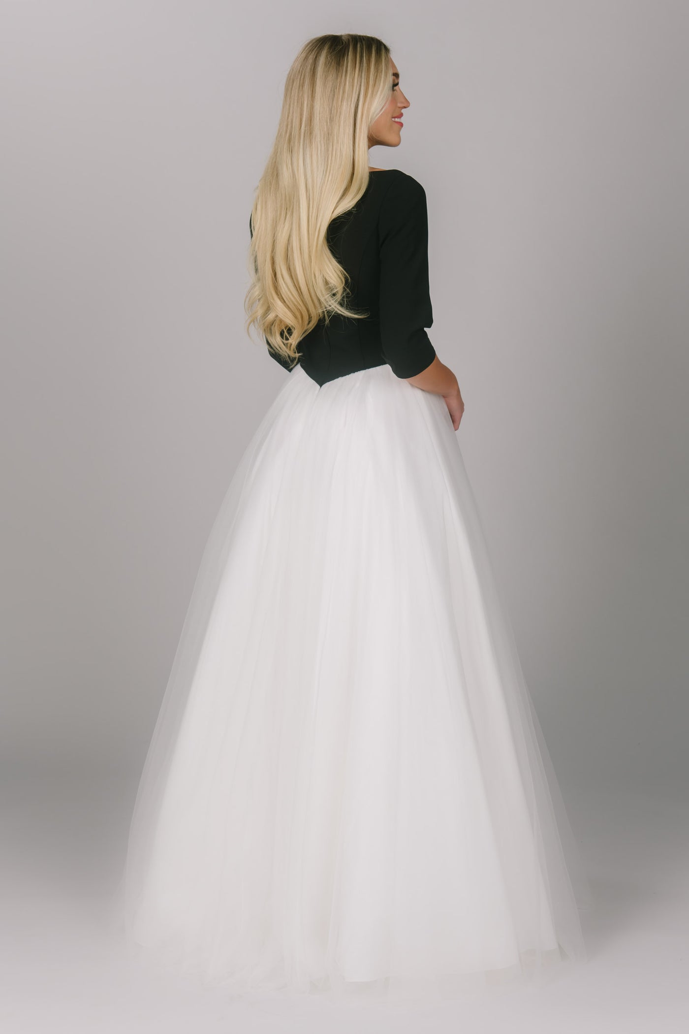 Modest prom ballgown with a white tulle skirt and black top. Sleeves are quarter length and it has a high scoop neckline. This is the perfect modest prom ballgown.