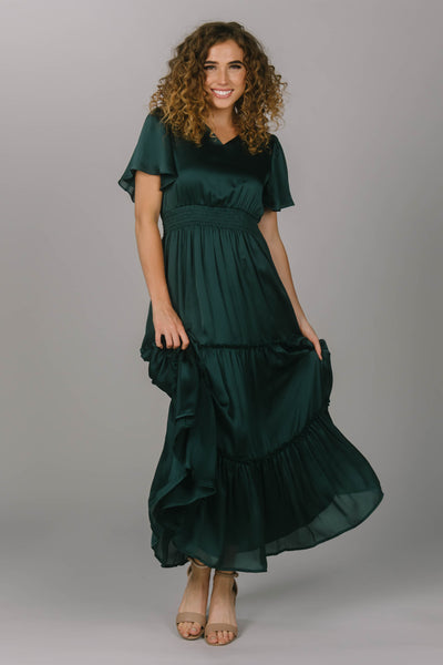Front view of the perfect green modest bridesmaid dress. It has a v-neckline, flutter sleeves, and tiered skirt. It has an extra shine on the fabric to make your modest bridesmaids really stand out. 
