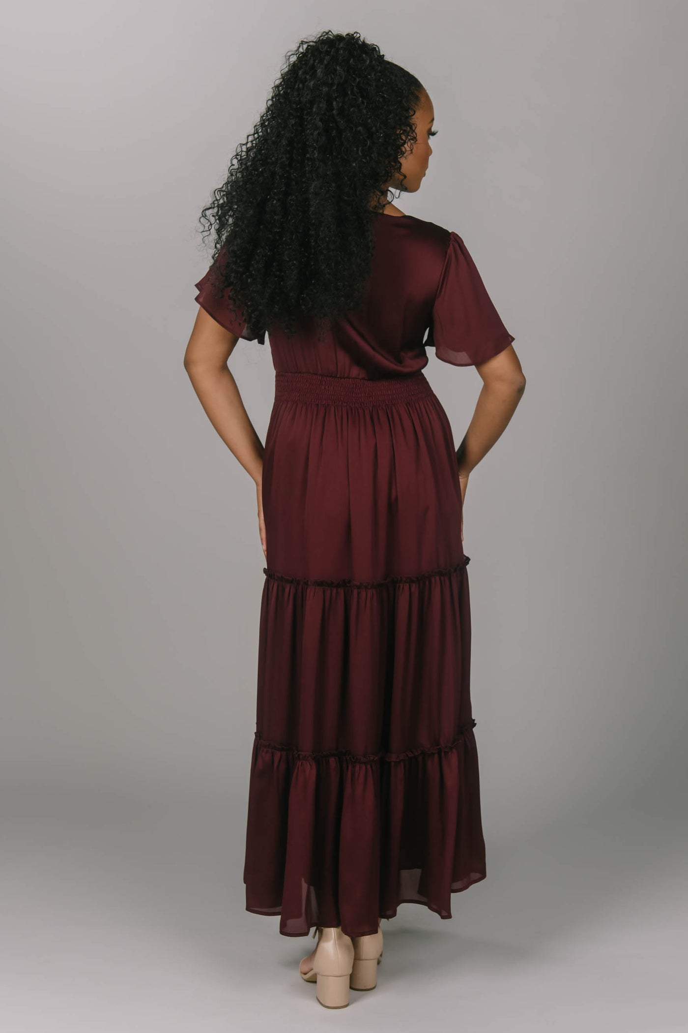 Modest bridesmaid dress with v neckline and flutter sleeves. This dress is a zinfandel color with a tiered skirt. This makes for the perfect modest bridesmaid dress for any season.