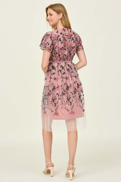 The back view of a knee length pink dress with a floral overlay and flutter sleeves at a modest dress shop in Bluffdale.