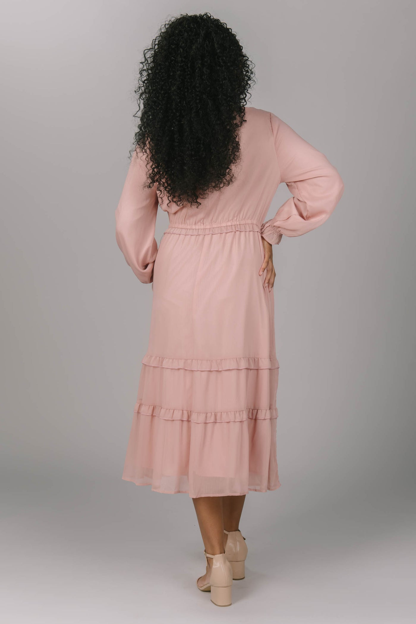 Back view of pink modest dress with long sleeves. It is tiered with buttons down the top of the dress. The modest bridesmaid would fall in love with this dress.