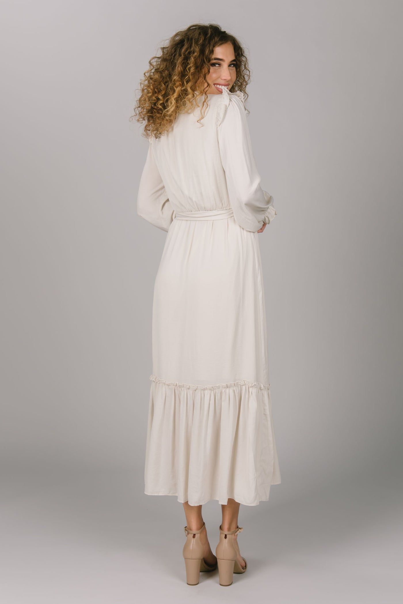 Back view of the Ivory modest everyday dress. It has a tie waist, long sleeves, and a tiered skirt. Everyday modest dress is perfect for a variety of occasions.