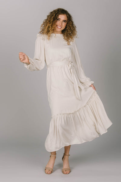 Front view of the Ivory modest everyday dress. It has a tie waist, long sleeves, and a tiered skirt. Everyday modest dress is perfect for a variety of occasions. 