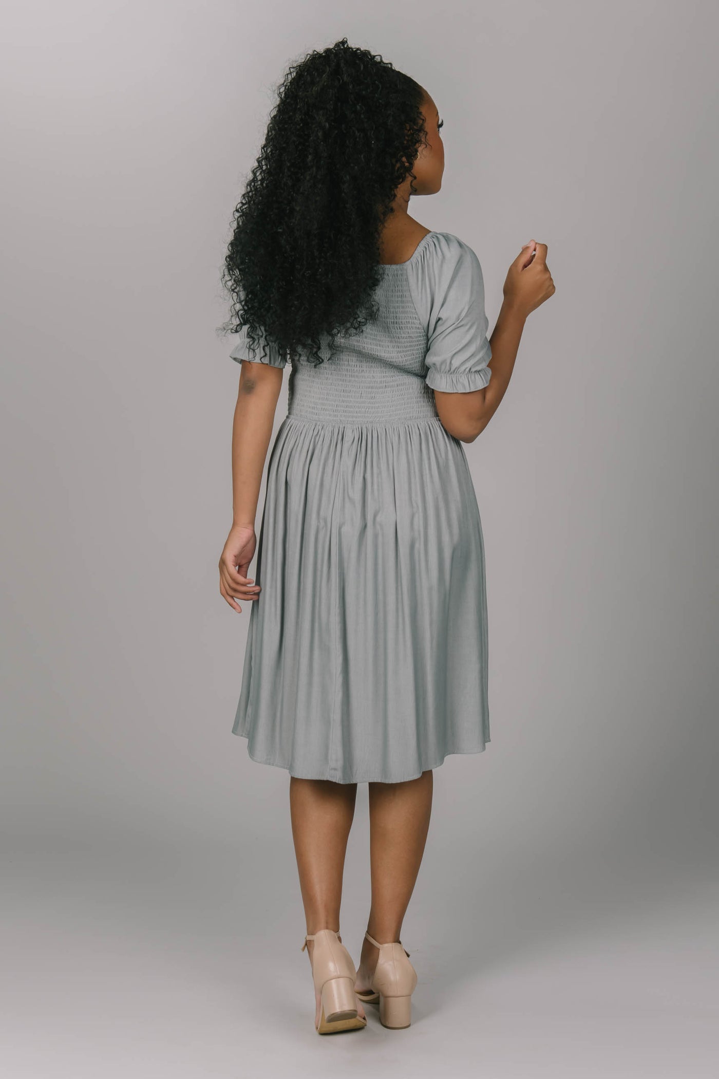 Back view of the smocked puff sleeve dress. It has a beautiful drizzle gray color. This modest dress has a square neckline and is knee length.