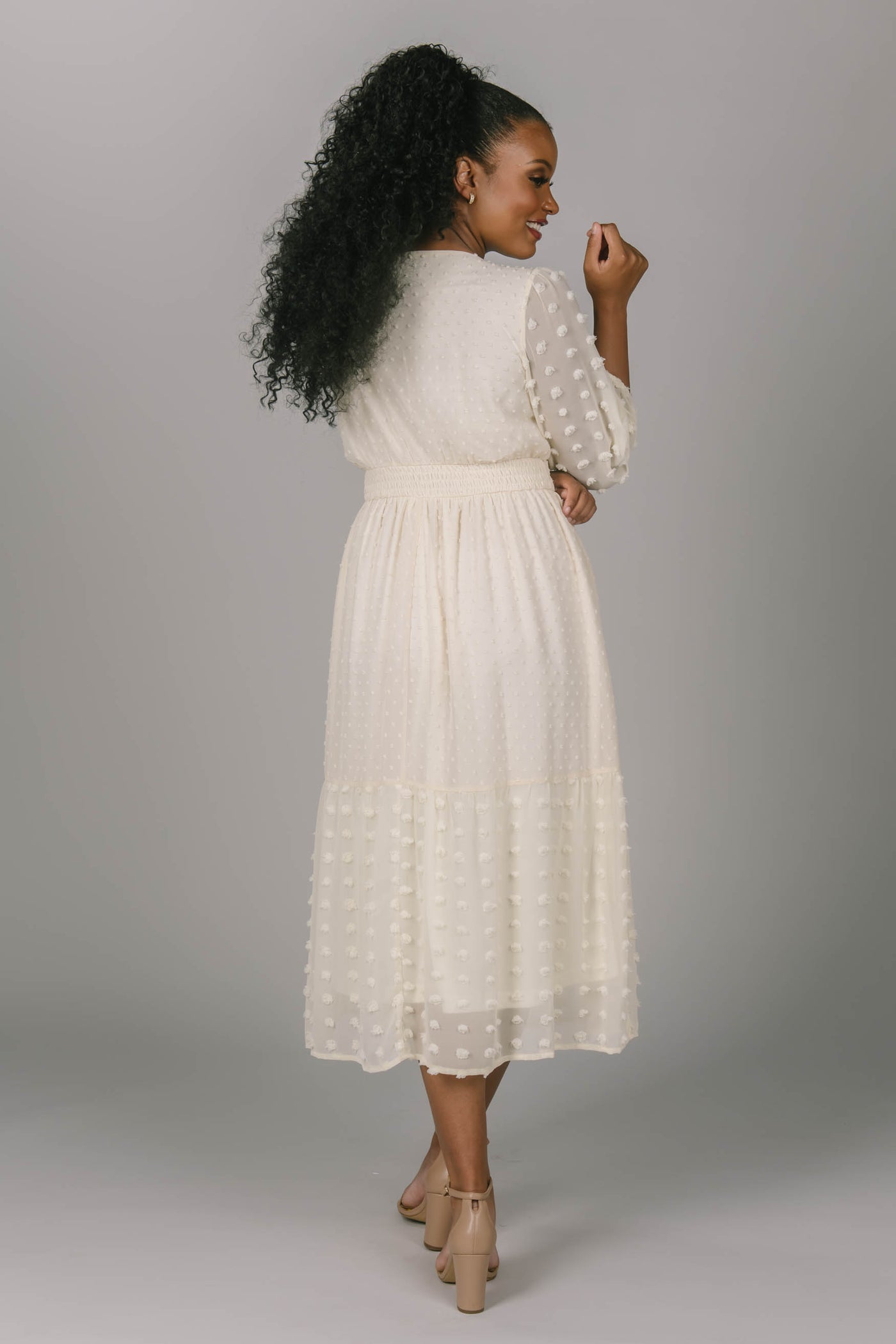 Back view of this modest Swiss dot dress. The length is mid-calf and the waist is cinched that has a square neckline and bishop sleeves. Modest women with a variety of skin tones look amazing in this dress.