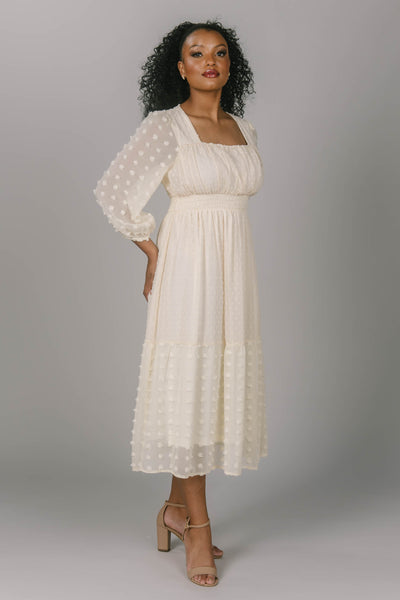 Front view of this modest Swiss dot dress. The length is mid-calf and the waist is cinched that has a square neckline and bishop sleeves. Modest women with a variety of skin tones look amazing in this dress. 